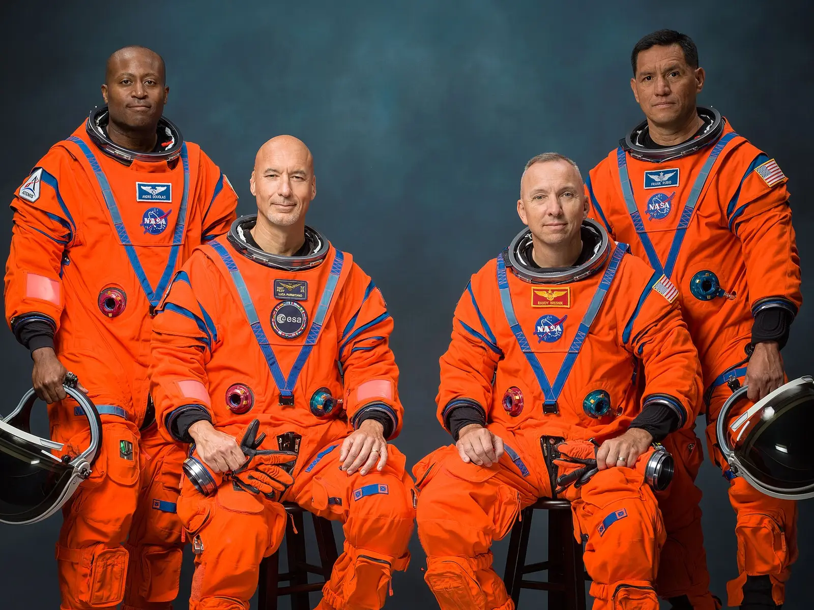 Čtyři astronauti Artemis III v oranžových kombinézách při oficiálním portrétu.