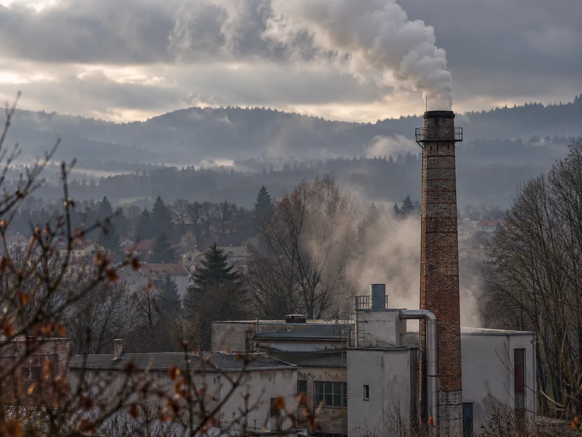 Teplárna s kouřícím komínem na okraji města za chladného podzimního rána.