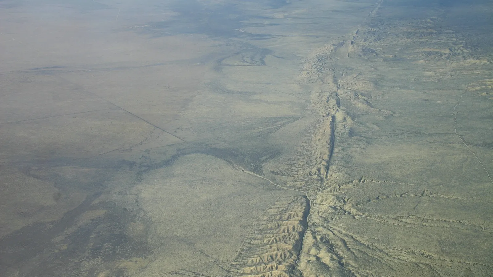 Letecký pohled na suchou planinu Carrizo, kterou napříč protíná zlom San Andreas jako dlouhá rovná čára mezi pahorky.